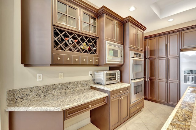 kitchen with light stone counters, stainless steel appliances, and light tile patterned flooring