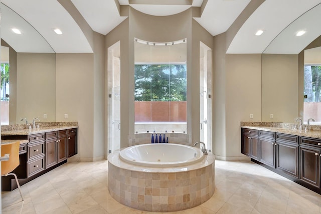 bathroom with a relaxing tiled tub and vanity