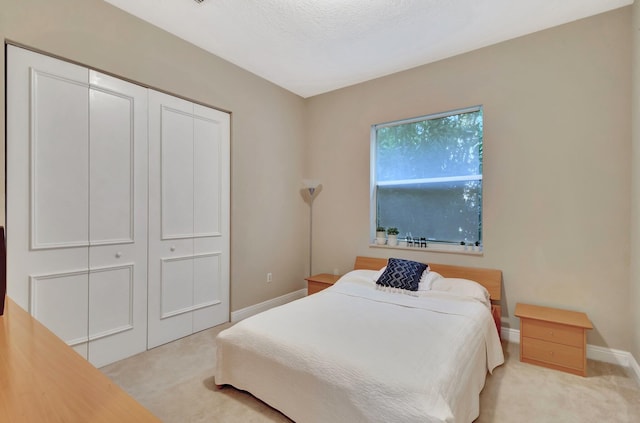 bedroom featuring light carpet, a closet, and a textured ceiling