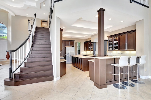 kitchen featuring stainless steel refrigerator with ice dispenser, light tile patterned flooring, a breakfast bar, and a center island