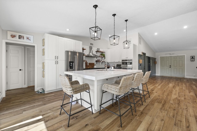 kitchen featuring a kitchen island with sink, a breakfast bar area, decorative backsplash, high end refrigerator, and white cabinetry