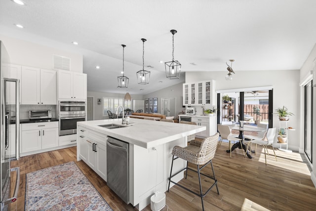 kitchen featuring a kitchen island with sink, vaulted ceiling, decorative backsplash, white cabinets, and sink