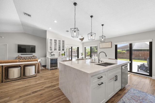 kitchen with dishwasher, an island with sink, wine cooler, white cabinetry, and sink