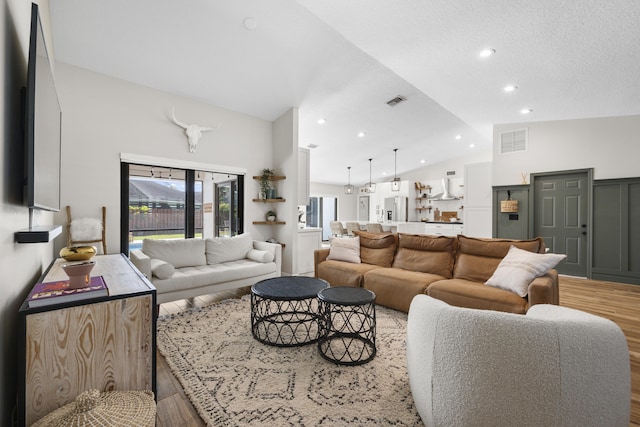 living room featuring vaulted ceiling and light hardwood / wood-style flooring