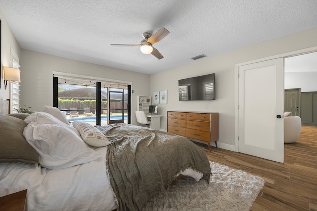 bedroom featuring ceiling fan, dark hardwood / wood-style floors, access to outside, and a textured ceiling