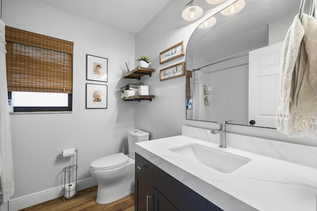 bathroom with toilet, curtained shower, vanity, and hardwood / wood-style floors