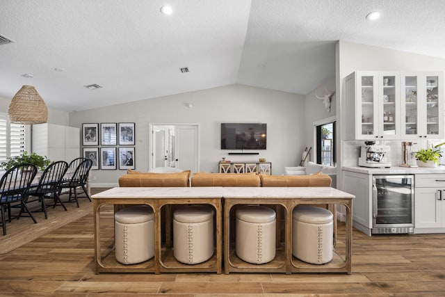 kitchen featuring white cabinets, beverage cooler, light hardwood / wood-style flooring, and a breakfast bar area