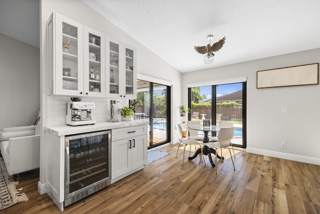 kitchen with dark hardwood / wood-style floors, tasteful backsplash, lofted ceiling, beverage cooler, and white cabinets