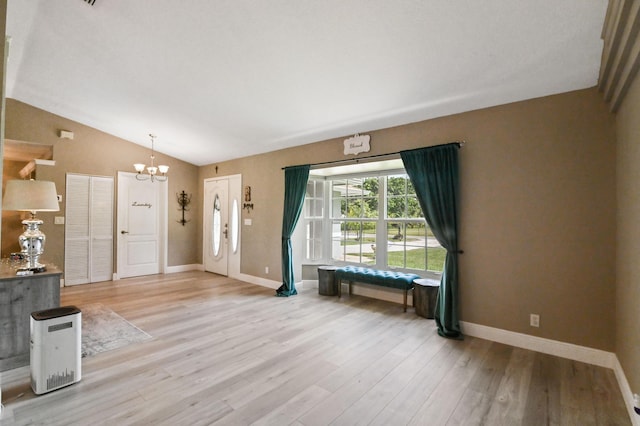 interior space with light hardwood / wood-style flooring, an inviting chandelier, and vaulted ceiling