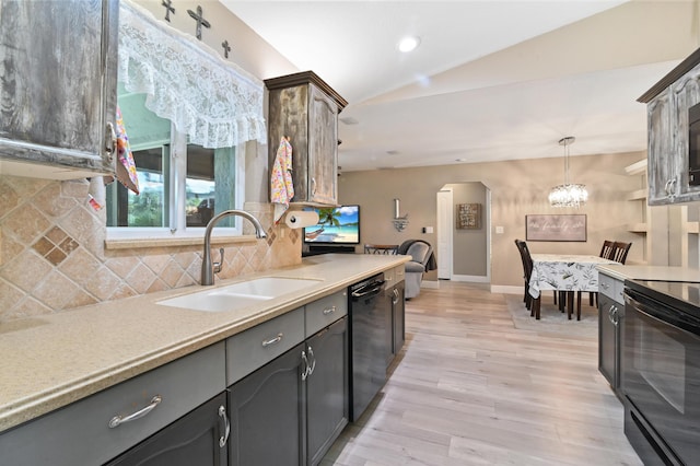 kitchen featuring decorative light fixtures, backsplash, black appliances, sink, and light hardwood / wood-style flooring