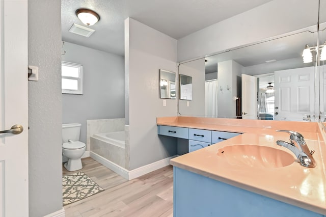 bathroom featuring toilet, vanity, wood-type flooring, and tiled tub