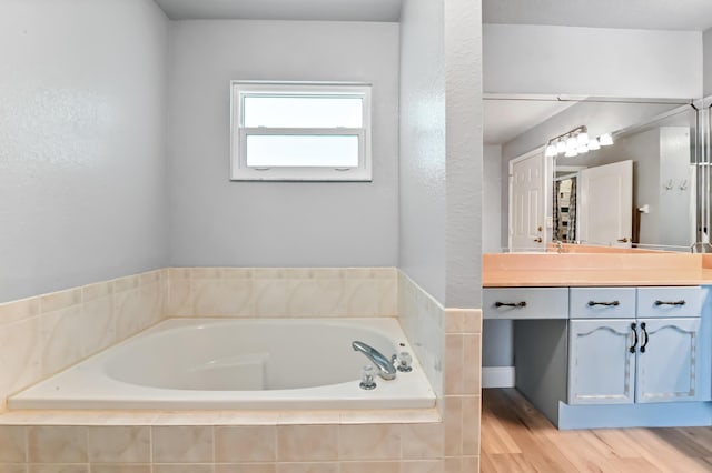 bathroom featuring tiled tub and vanity