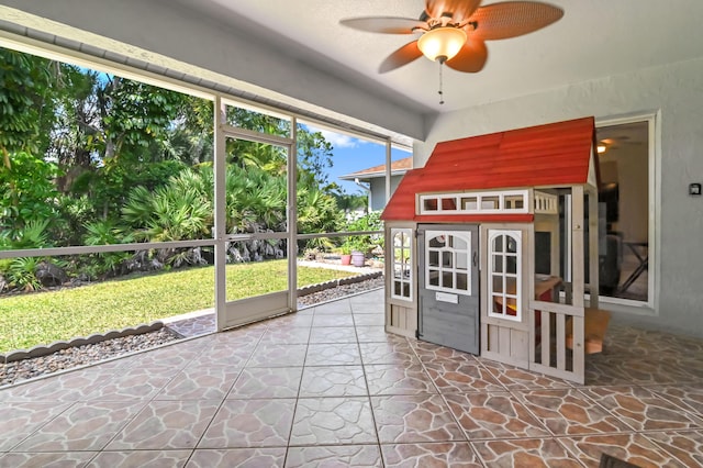 unfurnished sunroom featuring ceiling fan