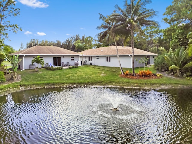 back of house with a water view and a lawn