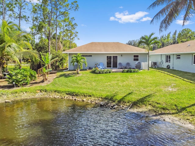 rear view of property featuring a water view and a yard