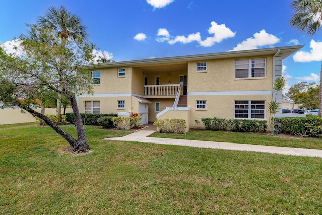 view of front of property featuring a front yard and a balcony