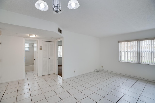 tiled spare room with a textured ceiling and a wealth of natural light