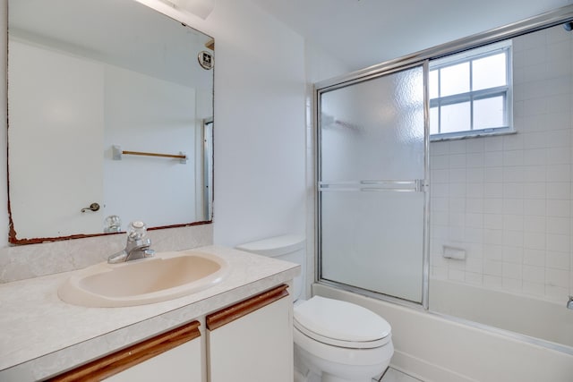 full bathroom with combined bath / shower with glass door, vanity, and toilet