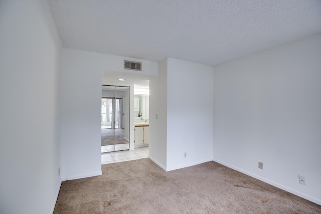 carpeted empty room featuring a textured ceiling