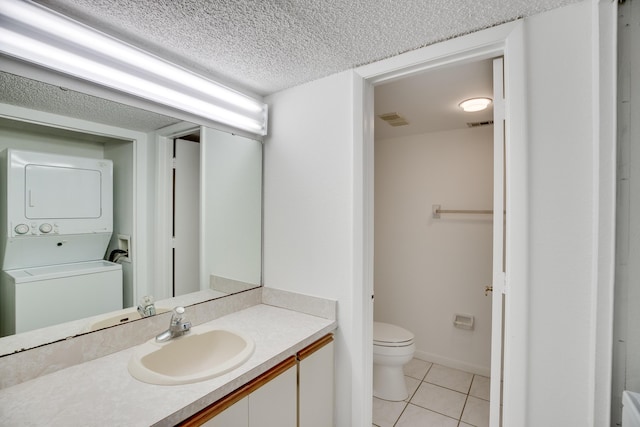 bathroom featuring a textured ceiling, toilet, tile patterned floors, stacked washer and dryer, and vanity