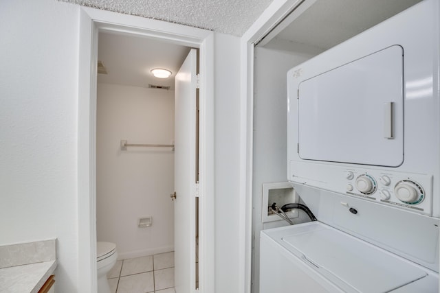 washroom featuring stacked washer / dryer and light tile patterned floors