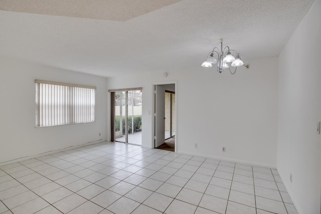 unfurnished room featuring a textured ceiling, a chandelier, and light tile patterned floors