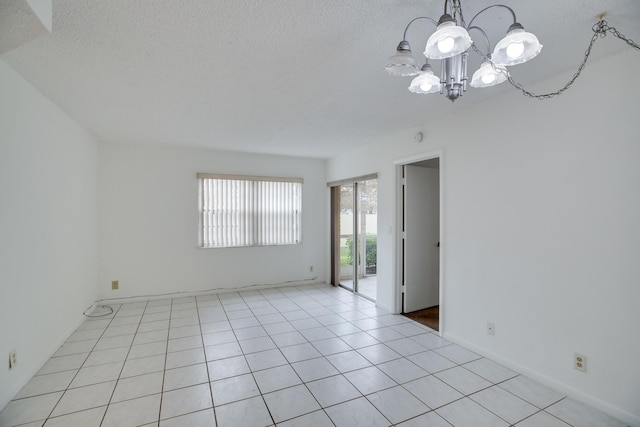 spare room with a chandelier and light tile patterned floors