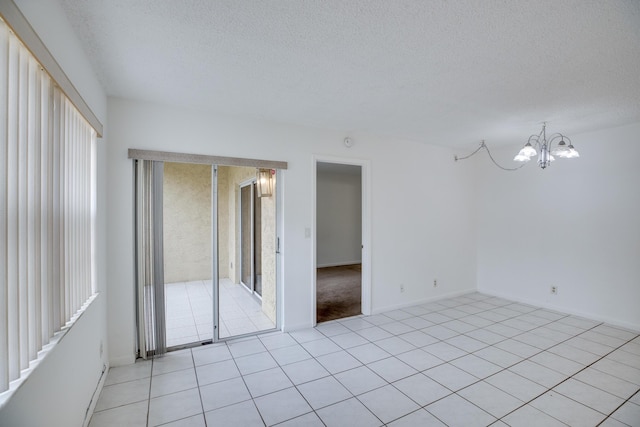 unfurnished room featuring a textured ceiling, an inviting chandelier, and light tile patterned floors