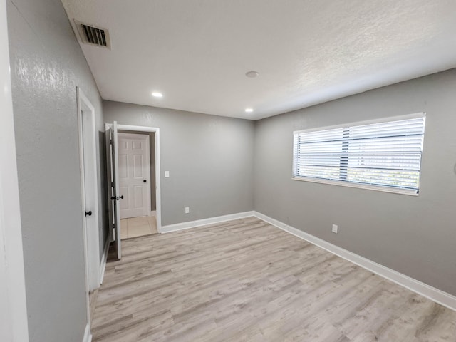 empty room featuring a textured ceiling and light hardwood / wood-style floors