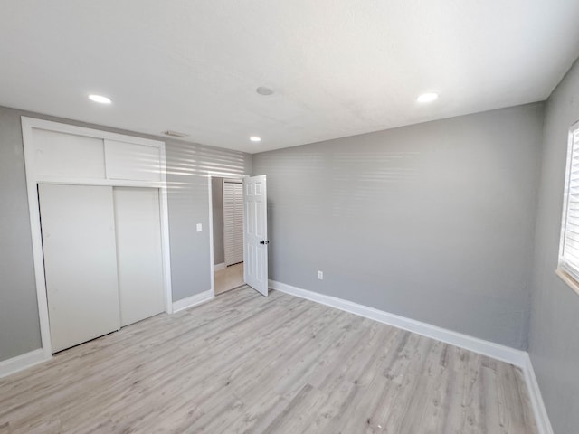 unfurnished bedroom featuring light wood-type flooring and a closet