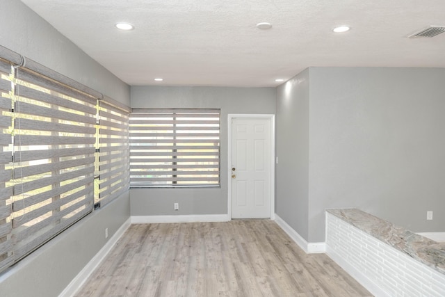 spare room featuring a textured ceiling and light hardwood / wood-style floors