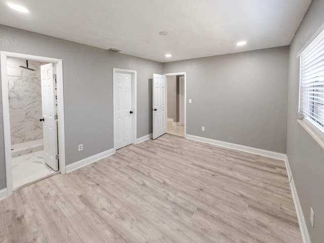 unfurnished bedroom with light hardwood / wood-style floors and connected bathroom