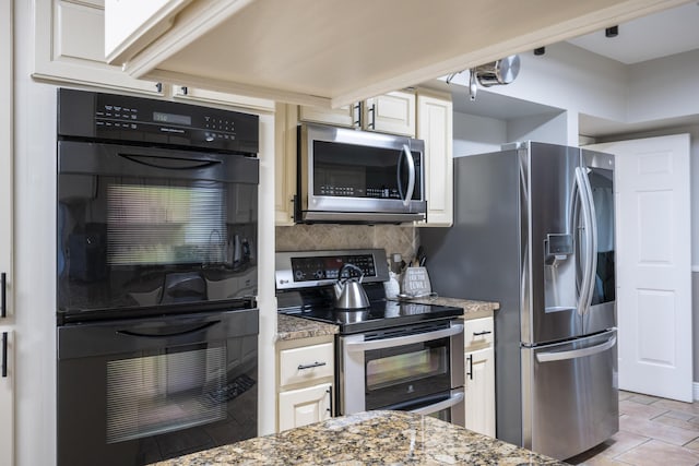 kitchen featuring backsplash, white cabinetry, appliances with stainless steel finishes, and dark stone counters