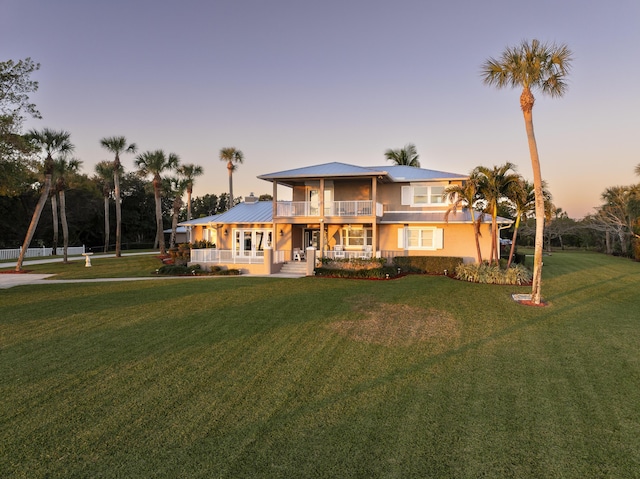 view of front of house featuring a balcony, a yard, and a porch