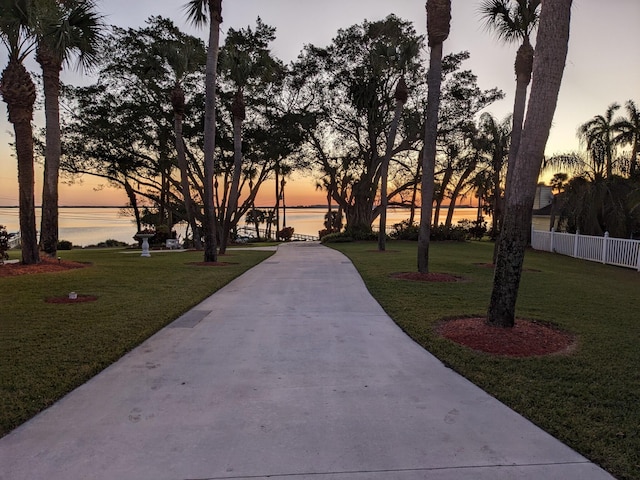 surrounding community with a water view and a yard