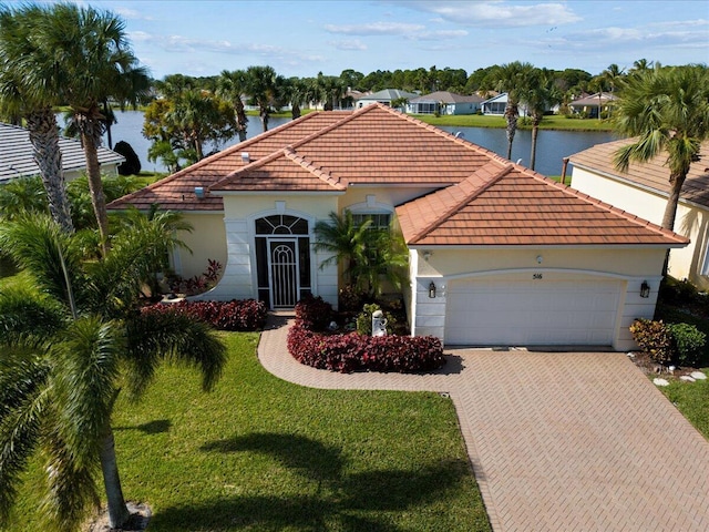 mediterranean / spanish home featuring a water view, a front lawn, and a garage