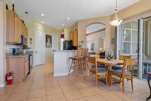 kitchen featuring decorative light fixtures, black refrigerator, decorative backsplash, range with electric stovetop, and light tile patterned floors