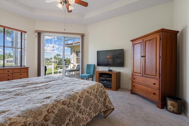 bedroom with ceiling fan, light carpet, a raised ceiling, and access to outside