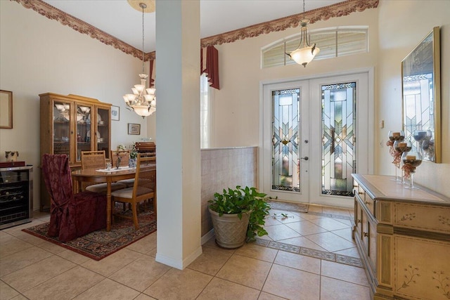 entrance foyer featuring light tile patterned floors, beverage cooler, french doors, and a notable chandelier