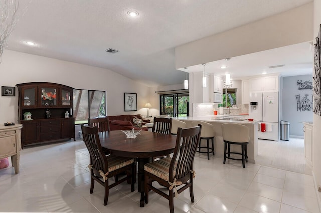 tiled dining room featuring vaulted ceiling