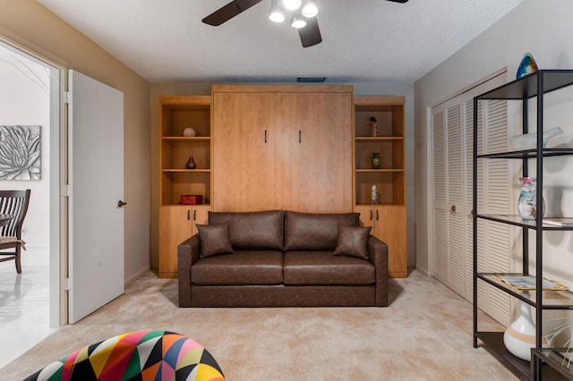 carpeted living room featuring a textured ceiling and ceiling fan