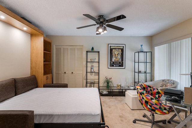 bedroom with ceiling fan, light colored carpet, a closet, and a textured ceiling