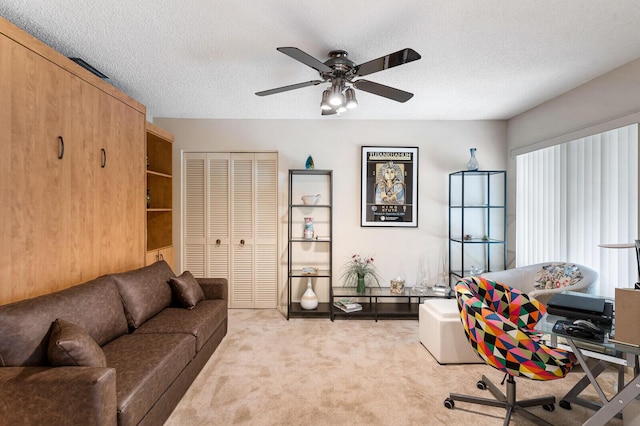 office featuring a textured ceiling, ceiling fan, and light carpet