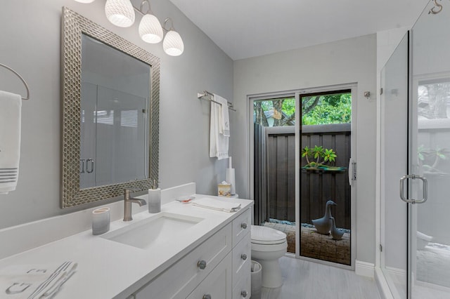 bathroom with toilet, a shower with door, and vanity