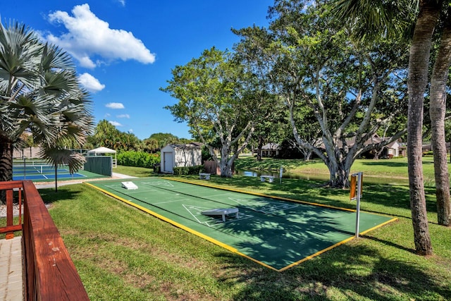 surrounding community with tennis court, a lawn, and a storage shed