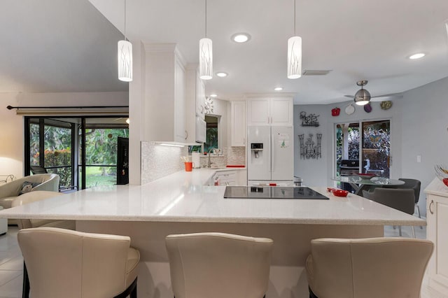 kitchen with black electric cooktop, hanging light fixtures, white refrigerator with ice dispenser, and kitchen peninsula