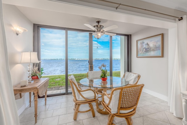 dining space featuring ceiling fan, light tile patterned floors, expansive windows, and a water view