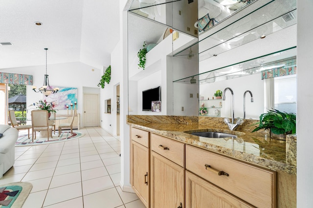 kitchen featuring vaulted ceiling, sink, hanging light fixtures, light tile patterned floors, and light brown cabinets