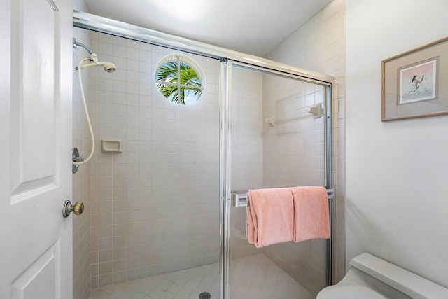 bathroom with a shower with door and toilet