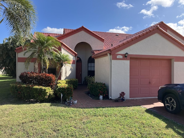 mediterranean / spanish-style home featuring a garage and a front lawn